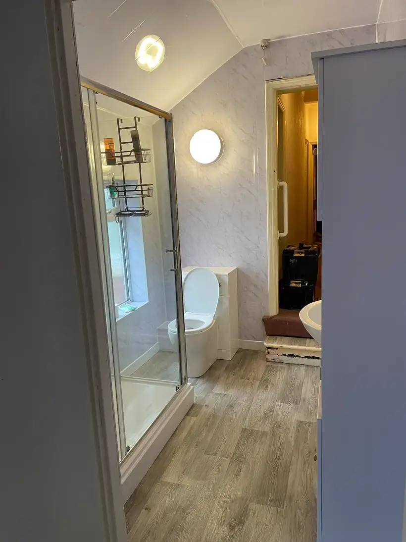 Glass shower enclosure fitted in a loft bathroom with a wood-effect floor
