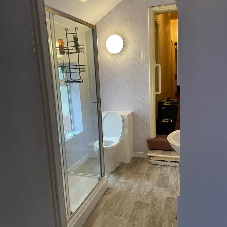 Glass shower enclosure fitted in a loft bathroom with wood-effect flooring